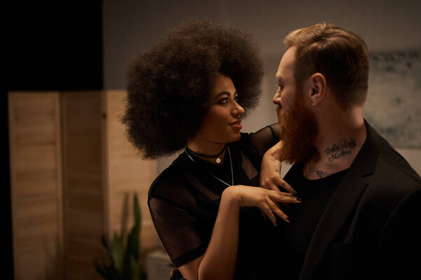 african american woman with curly hair in dress seducing tattooed boyfriend with beard, date night