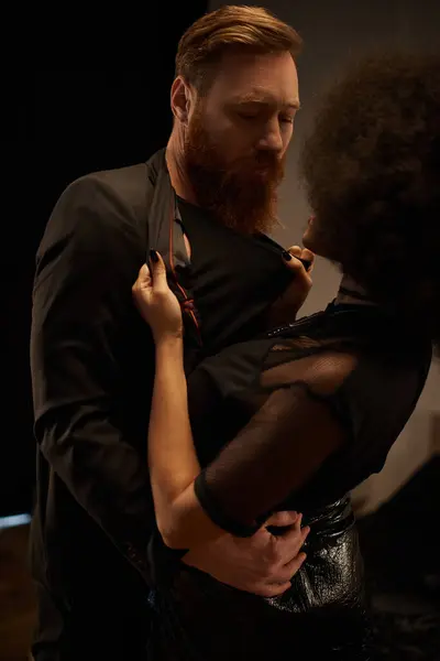 Stock image young african american woman in dress pulling blazer of bearded man during date, sexy couple