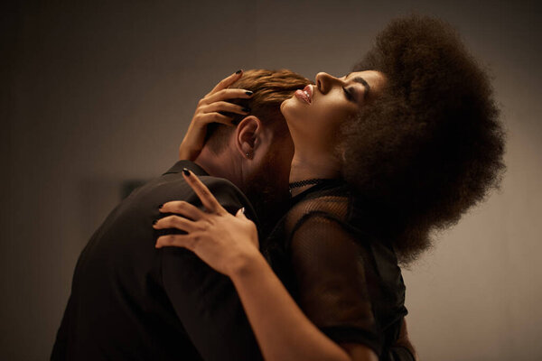 bearded man kissing neck of african american woman with curly hair, intimate moment of sexy couple