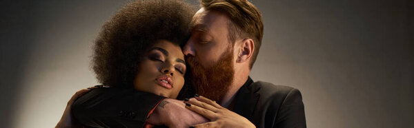 bearded man kissing african american woman with curly hair, intimate moment of sexy couple banner