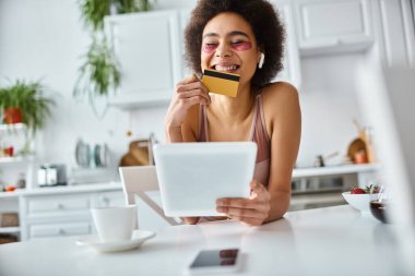 happy african american woman shopping online with tablet with credit card in hand, joy clipart