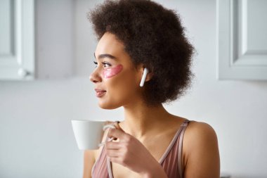 Serene moment with african american woman in earphones and lingerie sipping morning coffee, portrait clipart