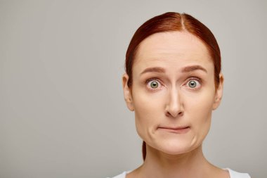redhead and worried woman in white tank top embodying concern on grey background, concerned face clipart