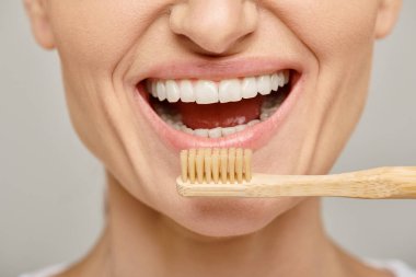 30 'lu yaşlarda elinde bambu bir diş fırçası olan, ağzı açık mutlu bir kadın resmi.