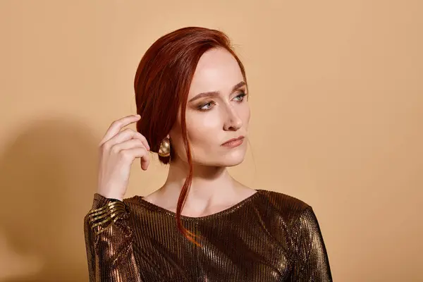 ベージュの背景にエレガントな衣装と黄金のアクセサリーでポーズ30代の魅力的な赤毛の女性 — ストック写真