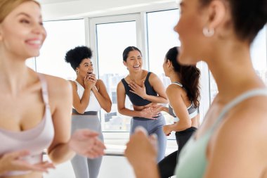 Spor kıyafetlerindeki çeşitli bayan arkadaşlara odaklanın. Pilates dersinden önce sohbet ederken kahkahalar atın.