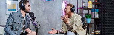 İyi görünümlü bir röportajcı ve kulaklıklı bir misafir stüdyoda sorular, podcast, pankart hakkında konuşuyor.