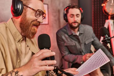 Her gün giyinmiş yakışıklı bir muhabir podcast sırasında konuğuyla soru soruyor.
