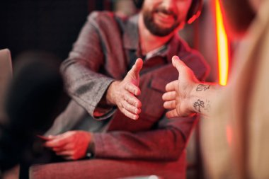 Stüdyoda podcastlar sırasında her gün rahat giyinen erkeklerin el sıkışması.