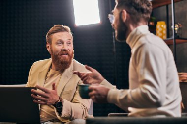 Kahve ve dizüstü bilgisayarlı, zarif giyinmiş iki yakışıklı, röportaj sorularını tartışıyorlar.
