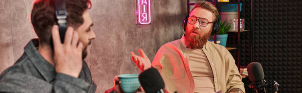 красивый интервьюер в стильной одежде, обсуждающий вопросы со своим гостем во время подкаста, баннера