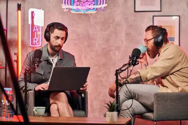 Podcast 'teki tartışmaları sırasında kahve ve dizüstü bilgisayarlı çok çalışkan adamlar
