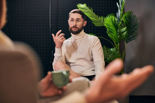 stock image attractive bearded man with glasses in elegant clothes sitting next to his interviewer in studio