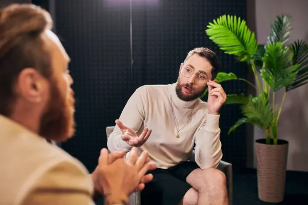 スタジオでのインタビューの質問に座って話し合うデボナエール服の専用のエレガントな男性 — ストック写真