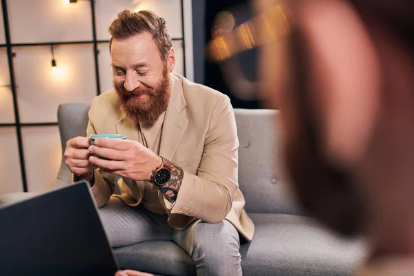 stock image two cheerful attractive men in elegant attires with coffee and laptop discussing interview questions