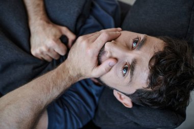 Günlük ev kıyafetleri içinde hayal kırıklığına uğramış yakışıklı bir adam çöküş sırasında kanepede yatar, zihinsel sağlık farkındalığı