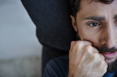 Stresli, sakallı, sıradan giyinmiş, zihinsel çöküntü sırasında elleri yüzükoyun uzanmış umutsuz bir adam.