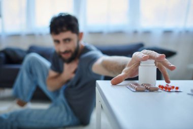 Masadaki haplara odaklanın. Arkaplanda depresif, zihinsel sağlık sorunu olan bulanık, endişeli bir adamla.
