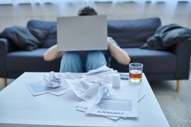 Depresyondaki sakallı adam laptopta çalışırken masada bir bardak alkol içiyordu.
