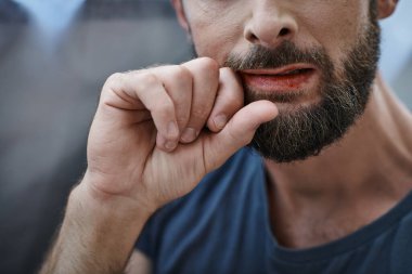 cropped view of anxious man with beard biting his lips till blood during depressive episode clipart