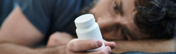desperate man with beard holding pills during depressive episode, mental health awareness, banner
