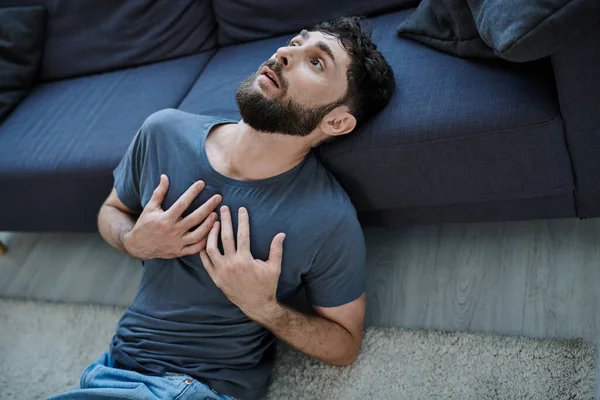 ill traumatized man with beard in home wear having severe panic attack, mental health awareness