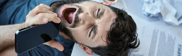 stock image frustrated man screaming at phone with glass of alcohol next to him during mental breakdown, banner