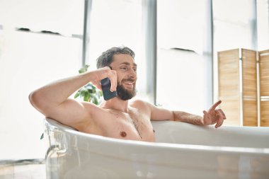 joyous good looking man with beard talking by phone while relaxing in bathtub, mental health clipart