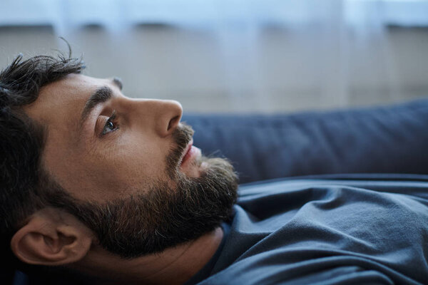 депрессивный тревожный человек с бородой в повседневной одежде лежал на диване во время психического срыва, осведомленности