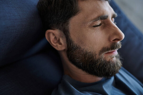 депрессивный тревожный человек с бородой в повседневной одежде лежал на диване во время психического срыва, осведомленности