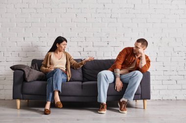 Evdeki oturma odasındaki koltukta oturan ırklar arası hoşnutsuz bir çift, aile boşanması kavramı.
