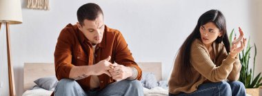 üzgün Asyalı bir kadın evde, yatak odasında kocasıyla tartışıyor, yatay afiş.