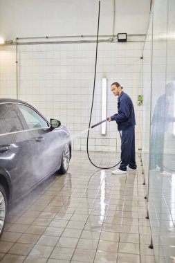 Garajda siyah araba yıkayan mavi rahat üniformalı yakışıklı bir asker.