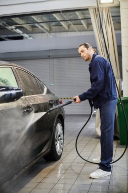 good looking dedicated serviceman in blue uniform with collected hair washing car carefully clipart