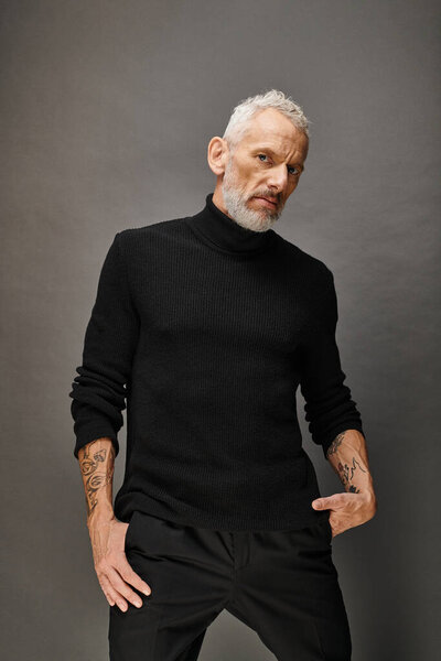appealing fashionable mature man with beard in trendy black turtleneck posing and looking at camera