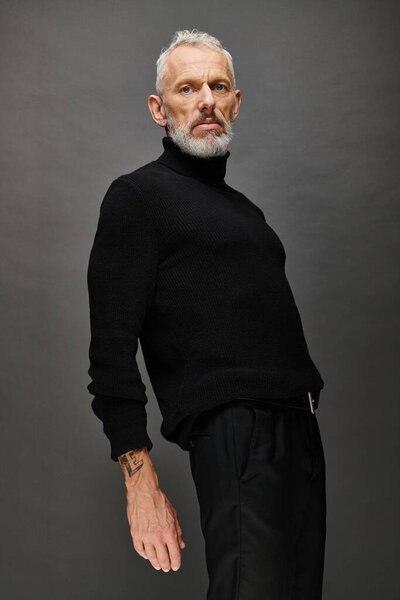 good looking fashionable mature man in stylish black turtleneck posing and looking at camera