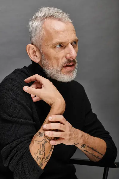 stock image appealing mature male model in fashionable turtleneck sitting on folding chair and looking away