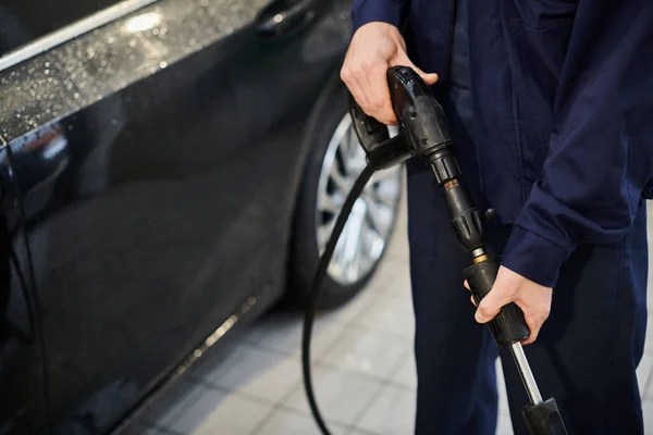 stock image cropped view dedicated hard working specialist in blue uniform preparing to use hose to wash car