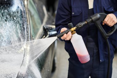 Mavi üniformalı çalışkan bir askerin sabunla araba yıkaması.