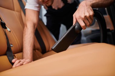 Aracın içinde elektrikli süpürge ile çalışan çalışkan profesyonel bir askerin kırpılmış görüntüsü