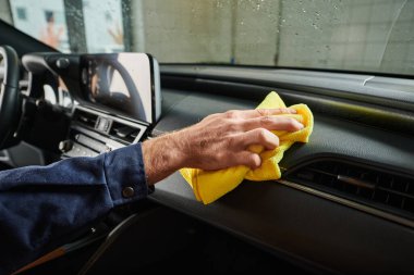 cropped view of hard working specialist in blue uniform cleaning glove compartment with rag clipart