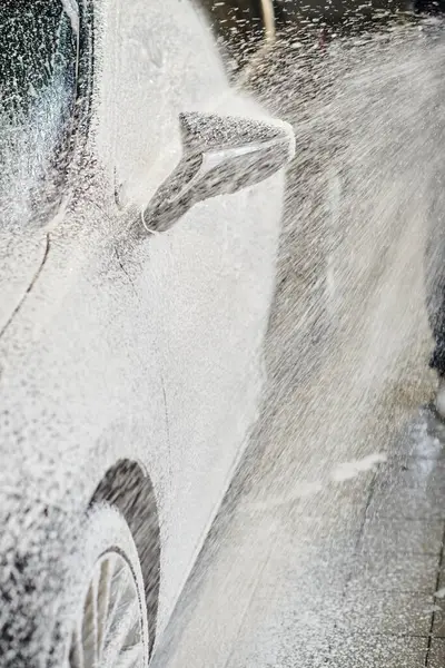 stock image cropped view of devoted professional worker holding hose and washing black modern car with soap