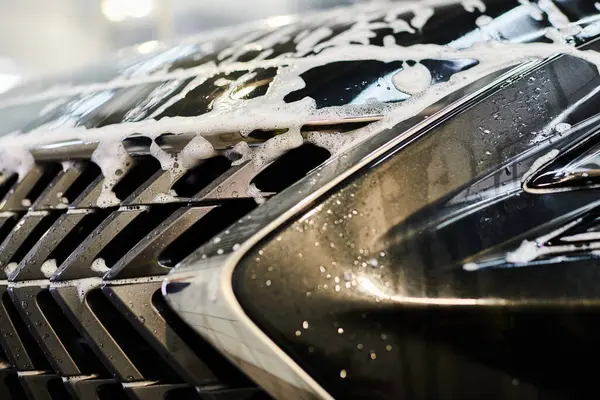 stock image object photo of shiny bumper of black modern car covered with soap during auto detailing process
