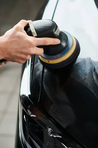 stock image cropped view of hard working serviceman using carefully polishing machine on black modern car