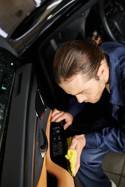 stock image good looking dedicated serviceman with collected hair in comfy uniform cleaning car with yellow rag