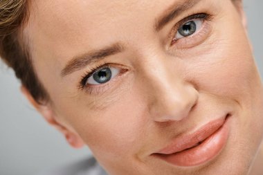 close up of cheerful beautiful woman with blonde hair and contact lenses looking at camera clipart