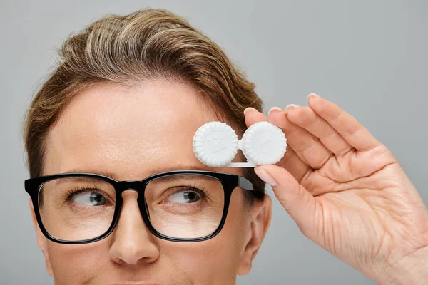 stock image happy attractive woman with blonde hair and glasses holding contact lenses and looking away