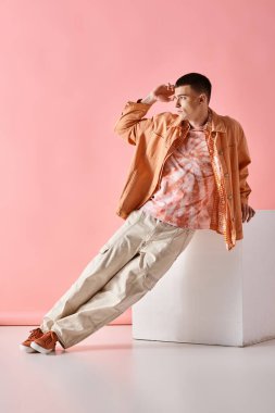 Bej gömlekli şık bir adamın moda imajı, pembe arka planda beyaz küplü pantolonlar ve botlar.