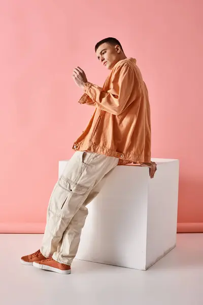stock image Full length image of stylish man in beige shirt, pants and boots on white cube on pink background