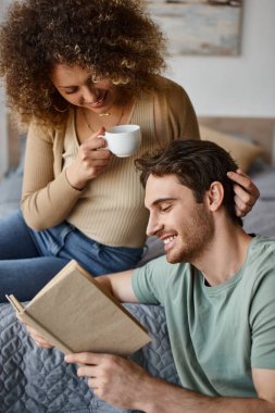 Kıvırcık genç kadın ve esmer adam ellerinde kitap, kahve içerken canlı sohbetler yaparlar.